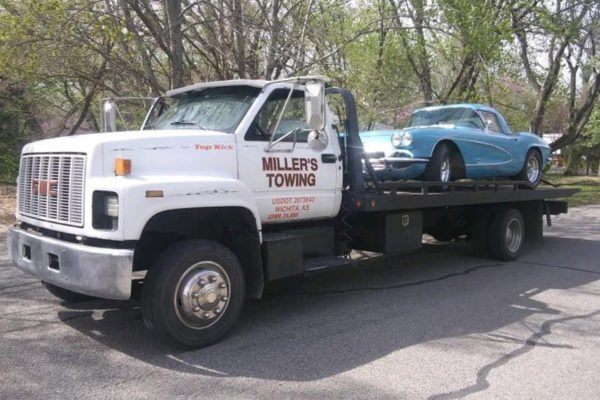White Miller's Towing ICT flatbed hauling a blue sedan in Wichita, Kansas
