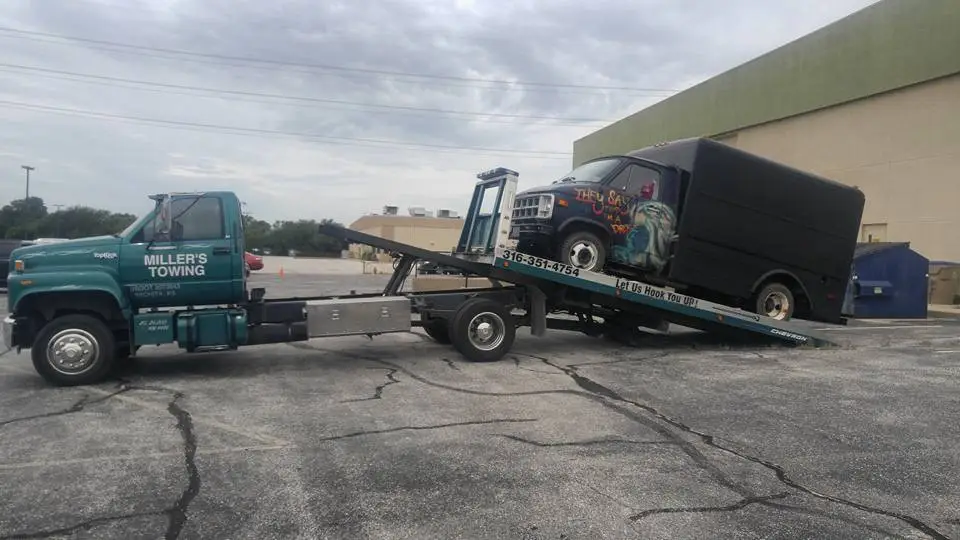 Tilted Miller's Towing flatbed loading a disabled vehicle onto the bed