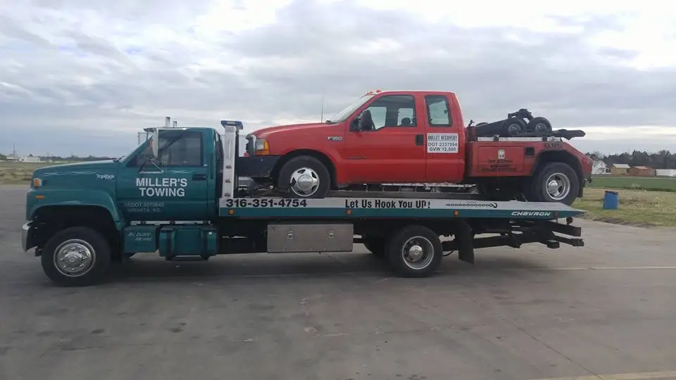 Miller's Towing flatbed carrying a red pickup truck in Wichita, KS