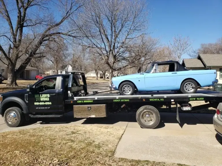 Miller's Towing flatbed hauling a vintage light blue pickup truck