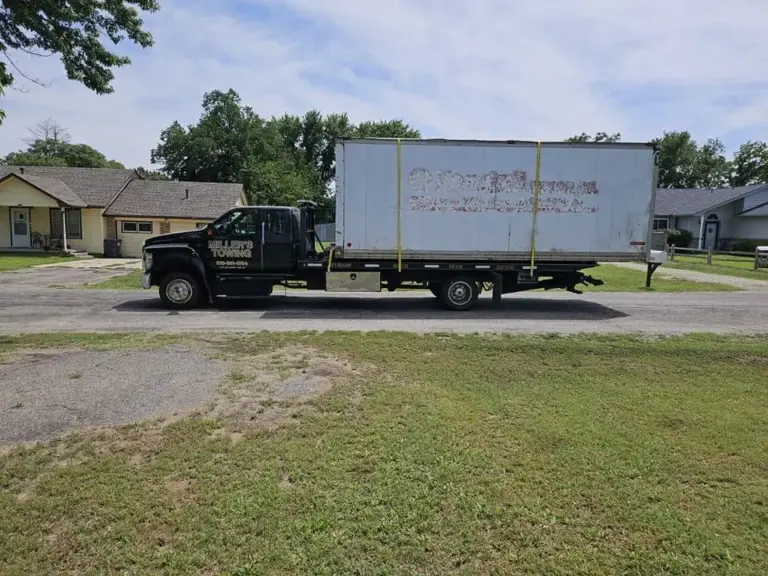 Miller's Towing flatbed hauling a box truck body through a Wichita neighborhood