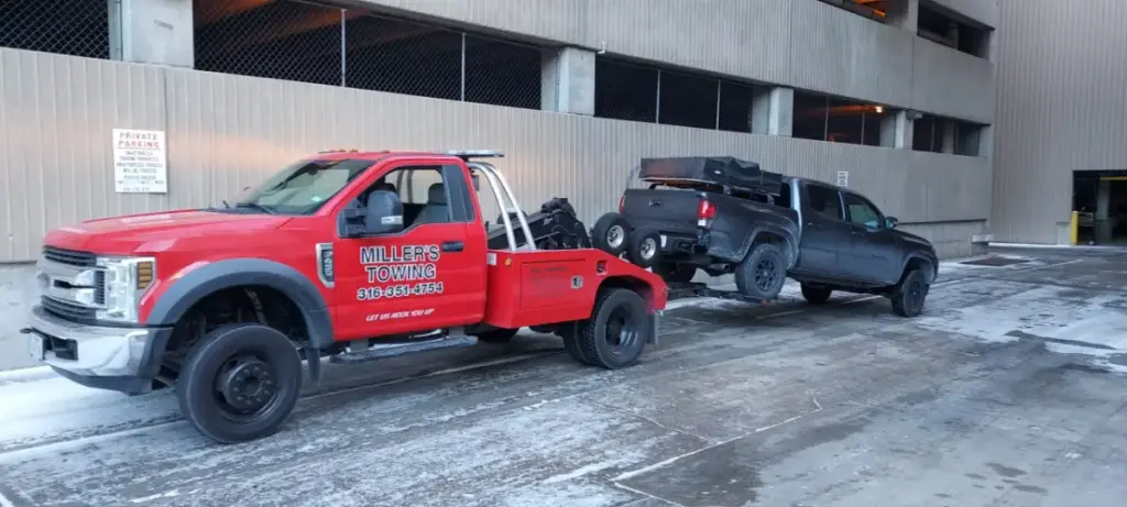 Red Miller's Towing wrecker removing an unauthorized pickup from a Wichita parking garage